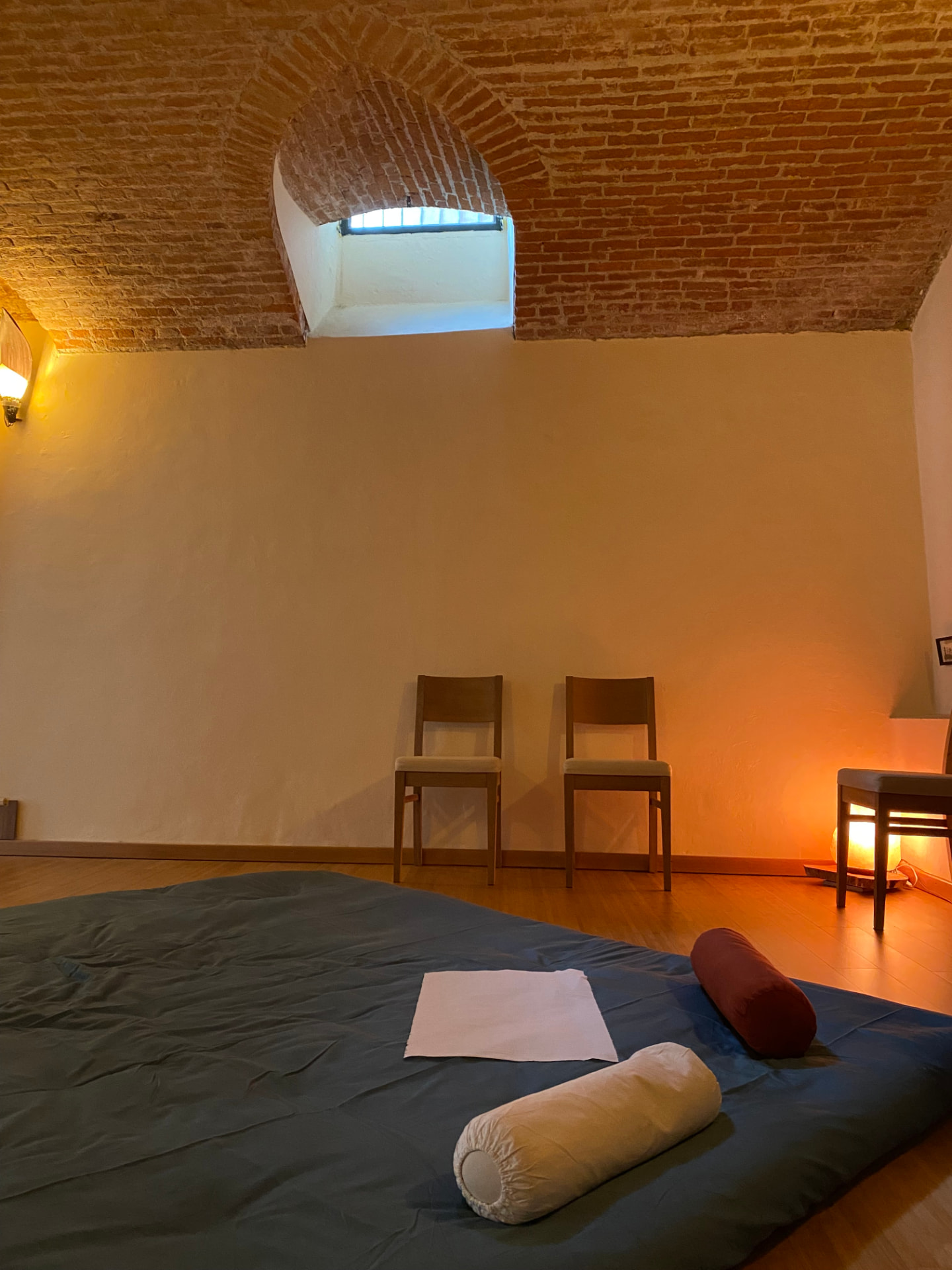 Angolo del vecchio studio di Laveno Mombello: materassino a terra, cuscini e lampada di sale sotto la volta in mattoni